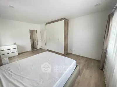 Spacious bedroom with modern design and ample natural light, featuring a large wardrobe and elegant flooring.