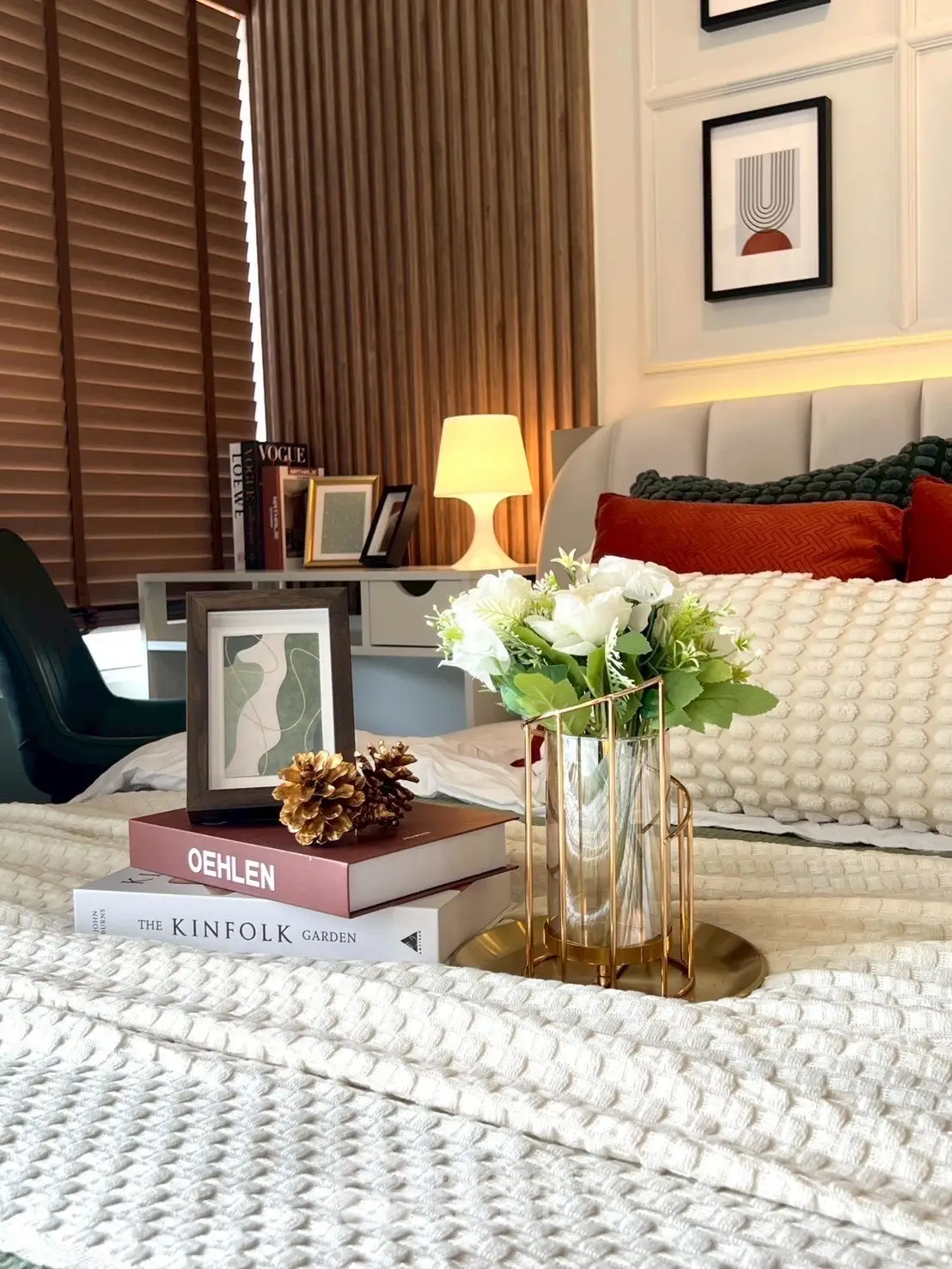 Cozy bedroom with stylish decor, featuring a plush bed, elegant lamp, and decorative books for a serene ambiance.