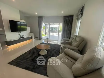 Modern living room with sleek furniture and large windows offering natural light and garden view.