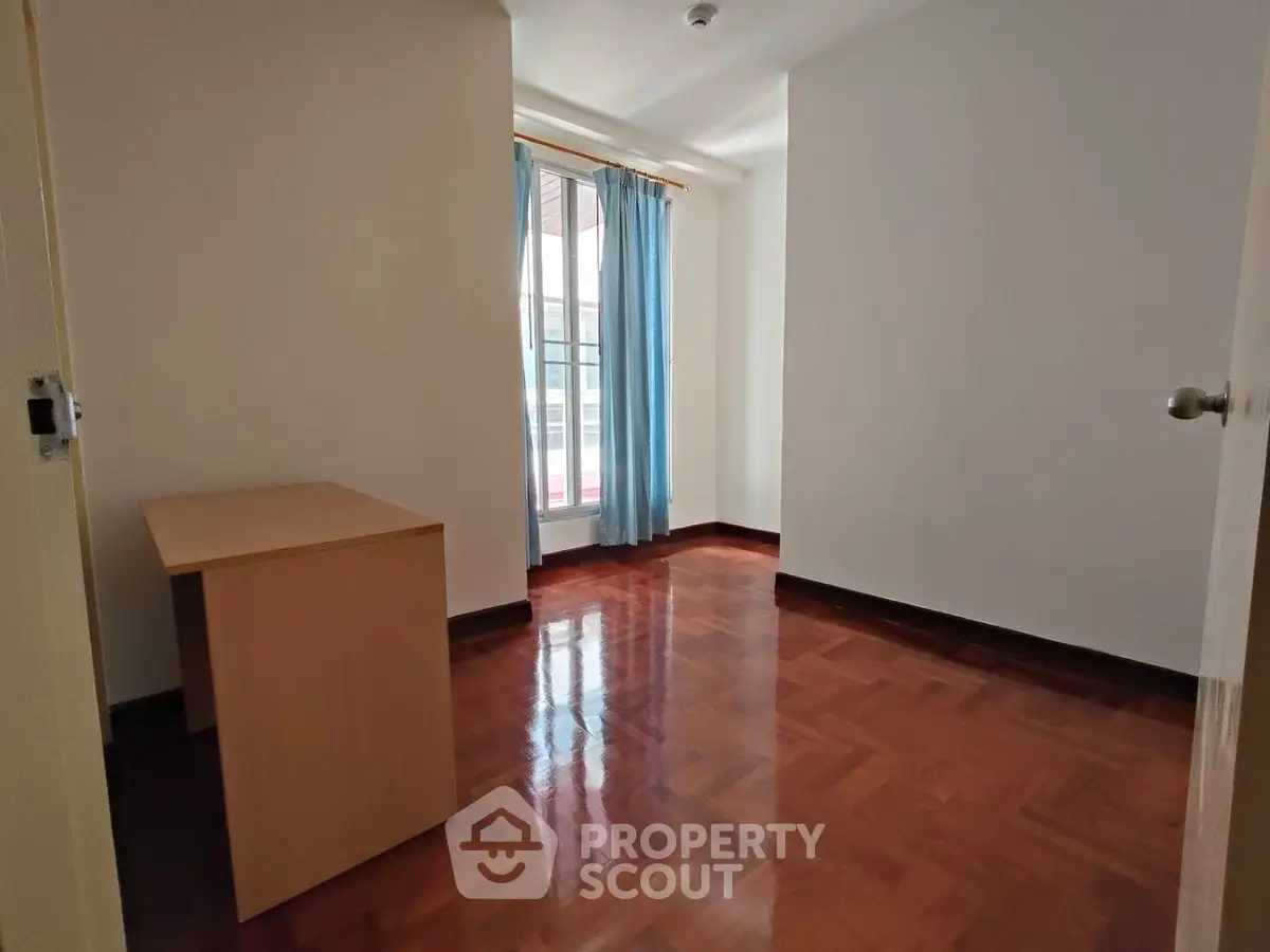 Spacious room with wooden flooring and natural light