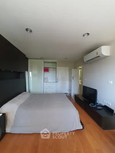 Spacious bedroom with modern furnishings and air conditioning unit, perfect for comfort and relaxation.