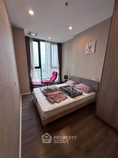 Modern bedroom with city view, featuring cozy bed and stylish decor in high-rise apartment.