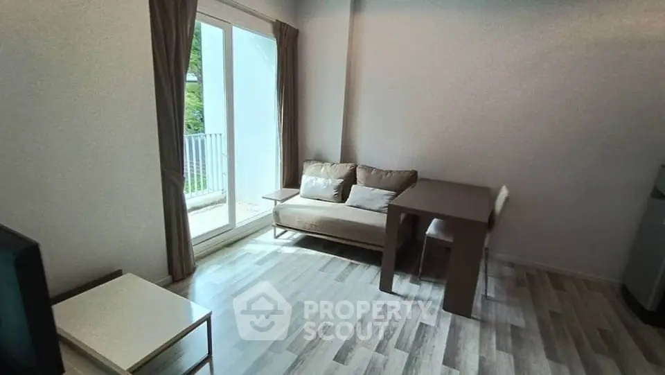 Cozy living room with natural light and balcony access in modern apartment.