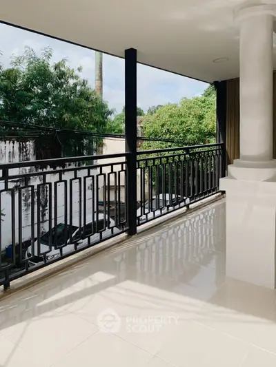 Spacious balcony with elegant railing and lush green view, perfect for relaxation.
