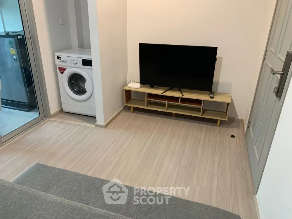 Modern living room with TV and washing machine in compact apartment