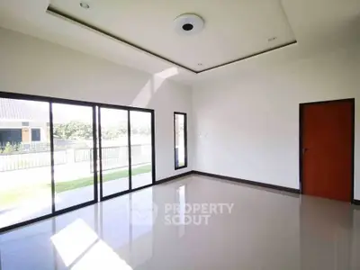 Spacious empty room with large windows and garden view, perfect for customization.