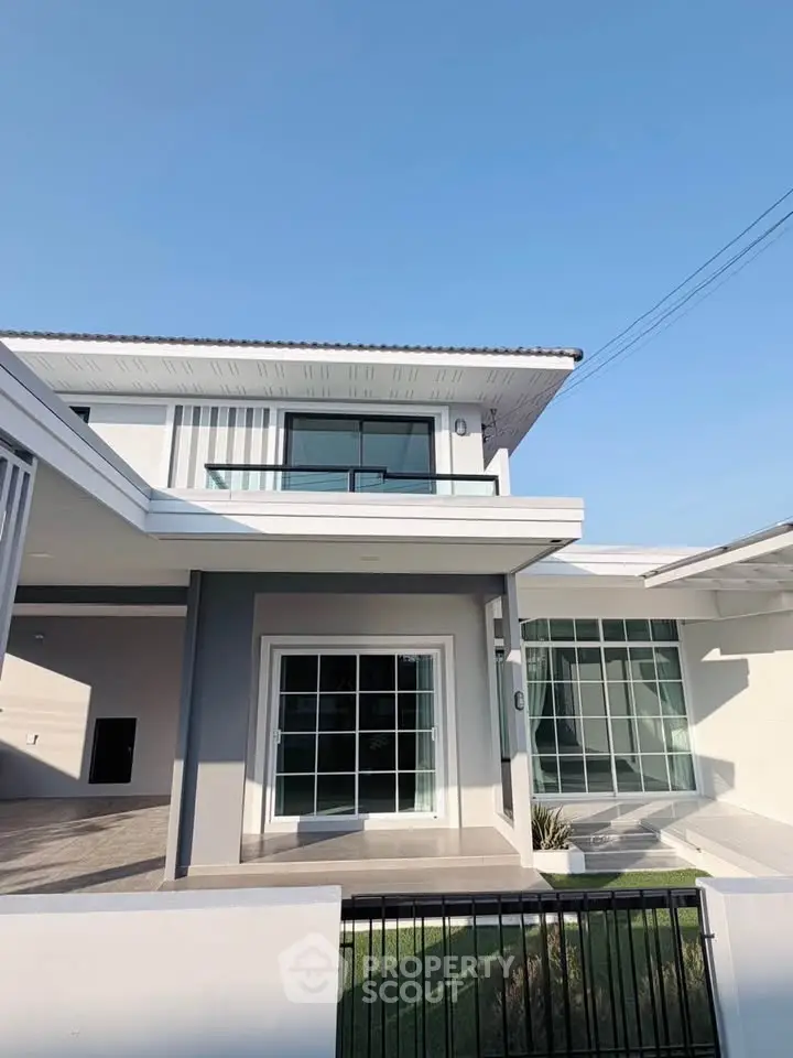 Modern two-story house with large windows and a spacious balcony, perfect for family living.