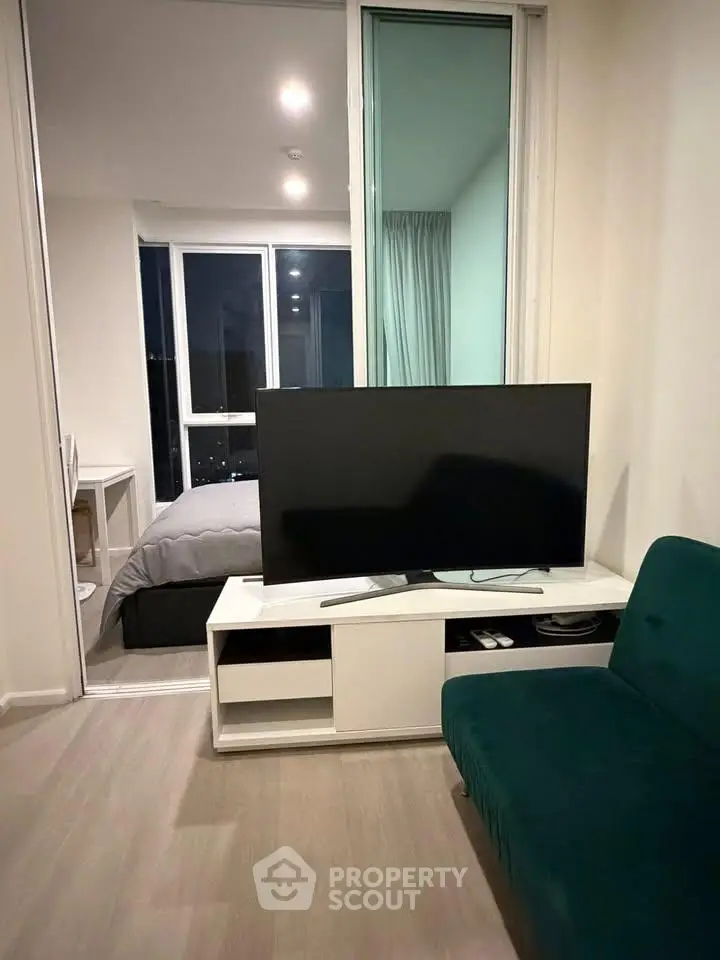Modern living room with TV and view into cozy bedroom in stylish apartment