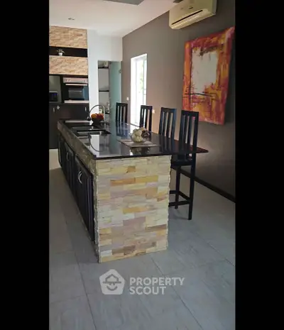 Modern kitchen with stylish island and bar stools, featuring sleek appliances and contemporary decor.