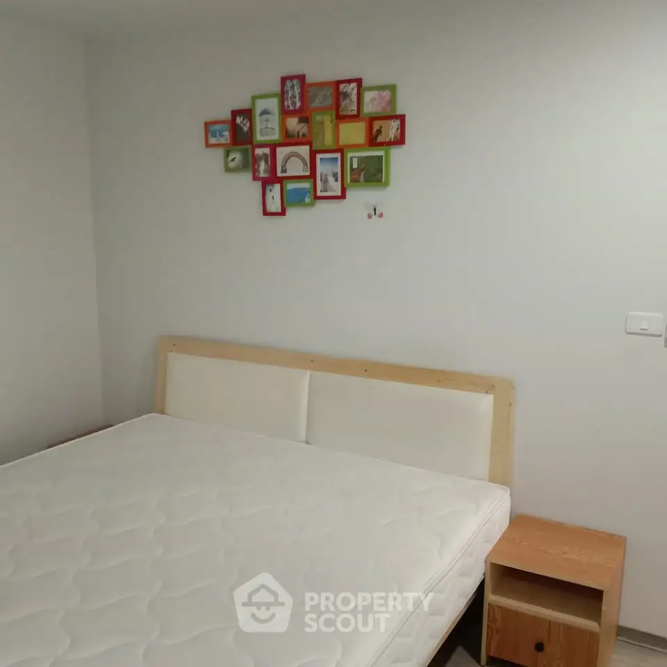 Cozy bedroom with a minimalist design featuring a comfortable bed and colorful wall art.