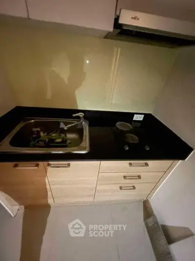 Compact kitchen with sleek black countertop and stainless steel sink