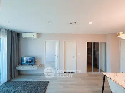 Modern living room with sleek design, featuring a wall-mounted TV, air conditioning, and elegant flooring.