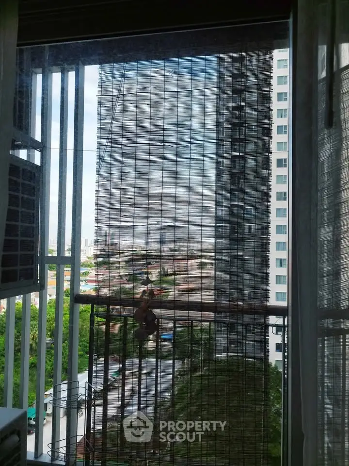 City view from apartment window with bamboo blinds and urban skyline.