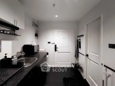 Modern kitchen with sleek black countertops and white cabinetry, featuring a compact layout and stylish design.
