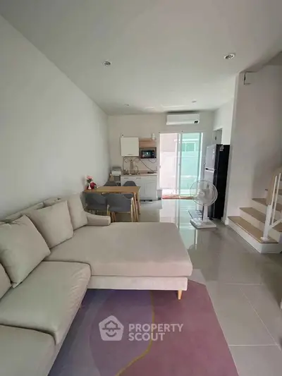 Modern living room with cozy beige sofa and dining area, open layout design.