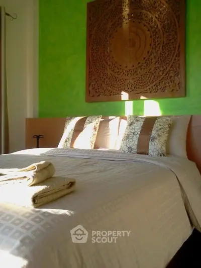 Cozy bedroom with elegant decor and vibrant green accent wall.