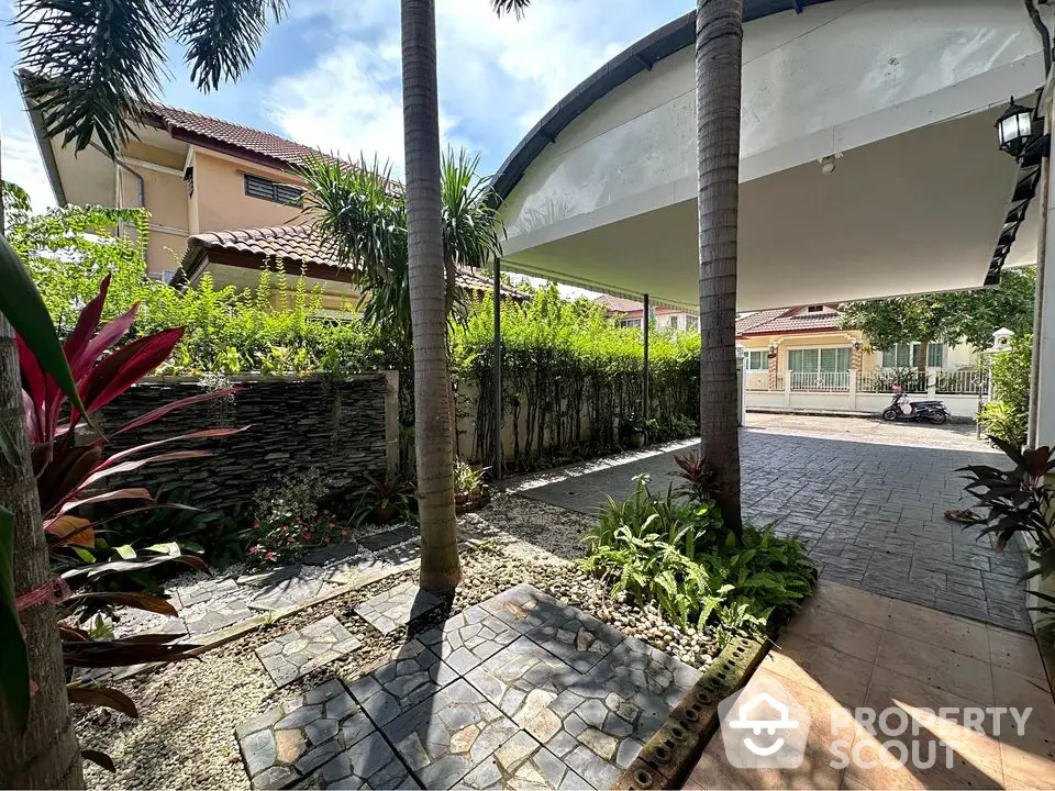 Charming garden entrance with lush greenery and paved pathway in suburban home.