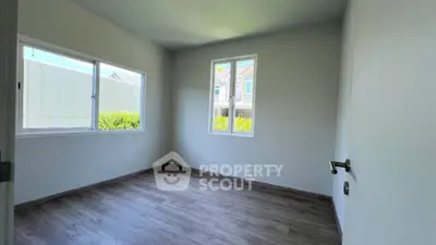 Bright empty room with large windows and wooden flooring, ideal for customization.