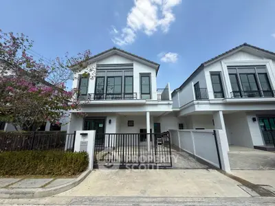 Modern two-story house with gated driveway and blooming tree