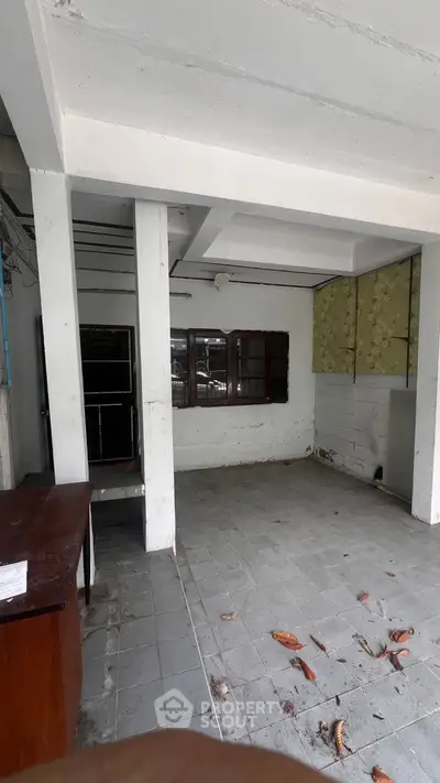 Spacious unfinished room with potential for renovation, featuring tiled floor and large window.