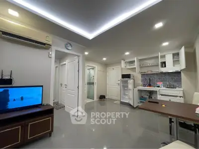 Modern open-layout living room with sleek kitchen and glossy flooring, featuring air conditioning and stylish lighting.