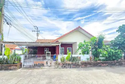 Charming single-story home with red accents and lush greenery in a peaceful neighborhood.