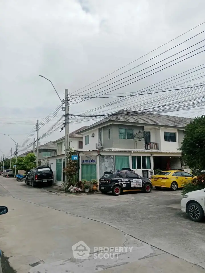Charming suburban house with driveway and parked cars in a peaceful neighborhood.