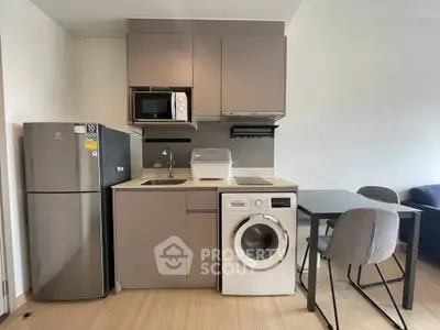 Modern compact kitchen with appliances including fridge, microwave, and washing machine in a cozy apartment.