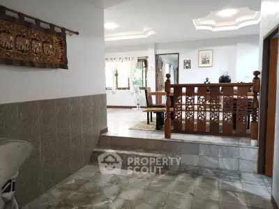 Spacious living area with elegant wooden railing and tiled flooring, perfect for family gatherings.
