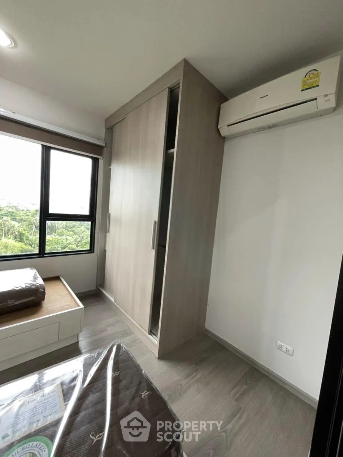 Modern bedroom with large window and built-in wardrobe, featuring air conditioning and scenic view.