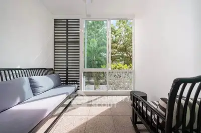 Bright living room with modern furniture and large window overlooking lush greenery.