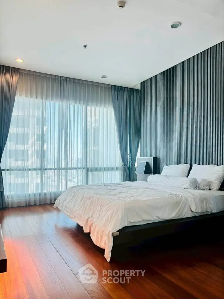 Luxurious bedroom with floor-to-ceiling windows and elegant decor in modern apartment.