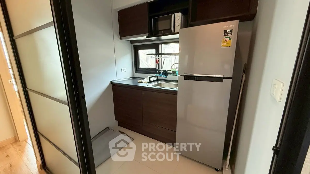 Compact kitchen with modern appliances and sleek cabinetry in a cozy apartment.