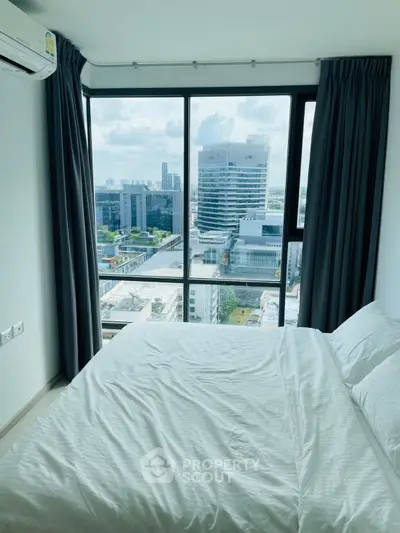 Modern bedroom with stunning city view from large windows in high-rise apartment.