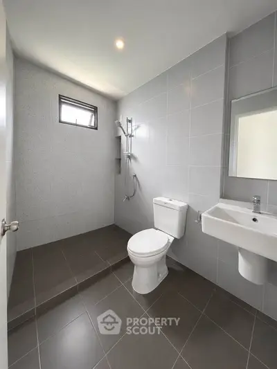 Modern minimalist bathroom with sleek gray tiles and walk-in shower design.