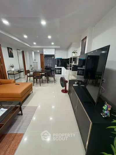 Modern open-layout living room with sleek furniture and large TV
