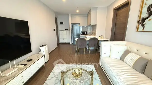 Modern living room with elegant decor and open kitchen layout, featuring stylish furniture and appliances.
