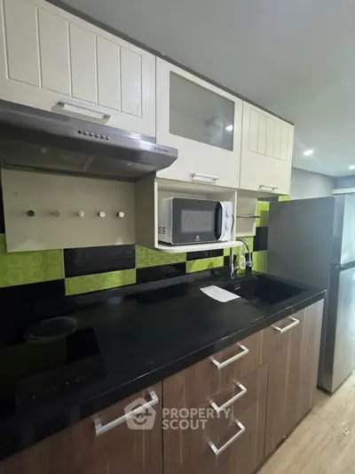 Modern kitchen with sleek cabinetry and appliances, featuring a microwave and stylish backsplash.