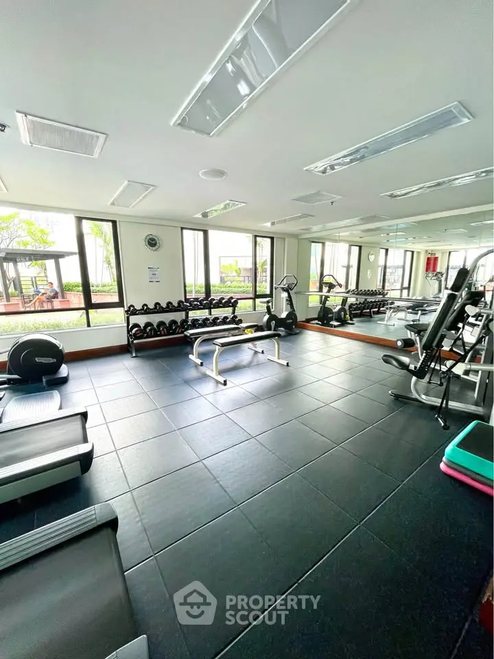 Spacious gym with modern equipment and large windows offering garden views.
