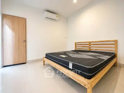 Spacious minimalist bedroom with wooden bed frame and air conditioning