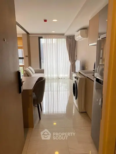 Modern apartment interior with open kitchen and living area featuring washing machine and sleek design.