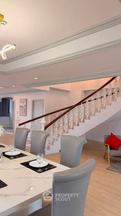 Elegant dining area with stylish staircase and modern decor in a luxurious home interior.