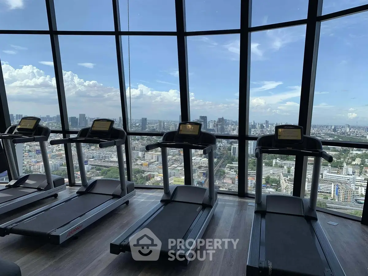 Stunning gym with panoramic city views and modern treadmills in a high-rise building.