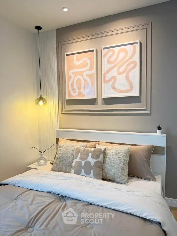 Modern bedroom with stylish decor and abstract art above bed, featuring cozy lighting and neutral tones.