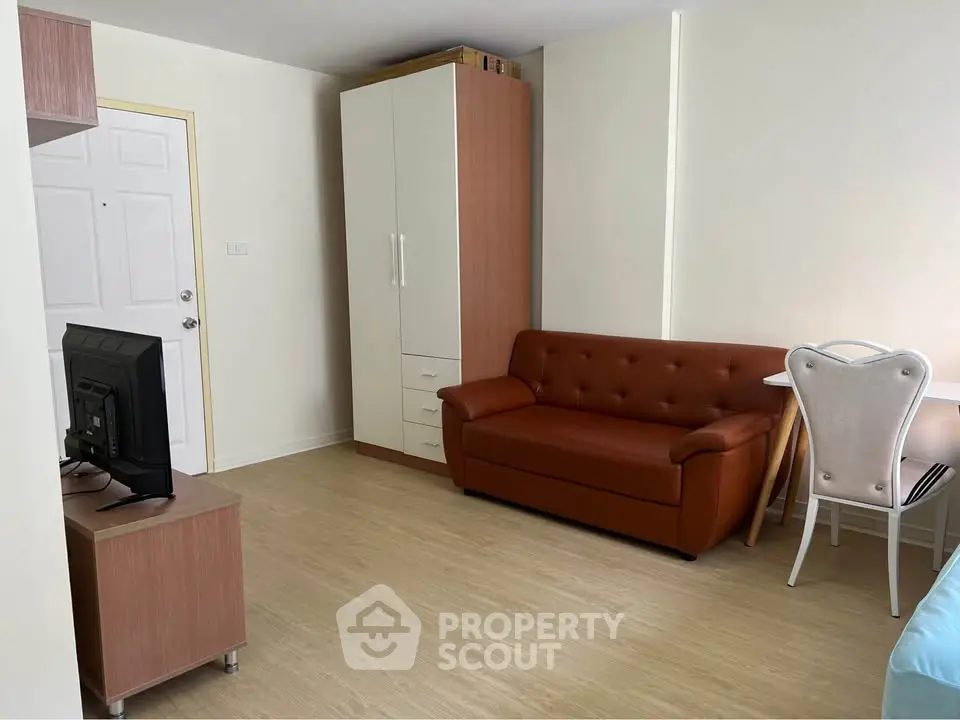 Cozy living room with leather sofa, TV, and wardrobe in modern apartment.