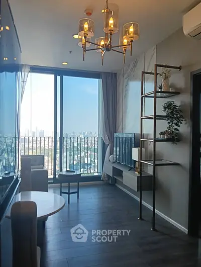 Modern living room with city view, elegant chandelier, and stylish decor.