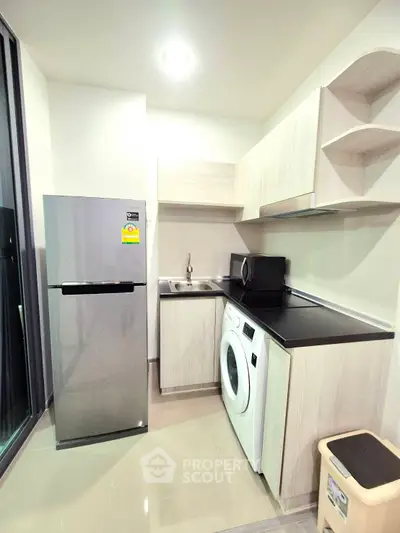 Modern kitchen with sleek appliances and washing machine in compact layout.