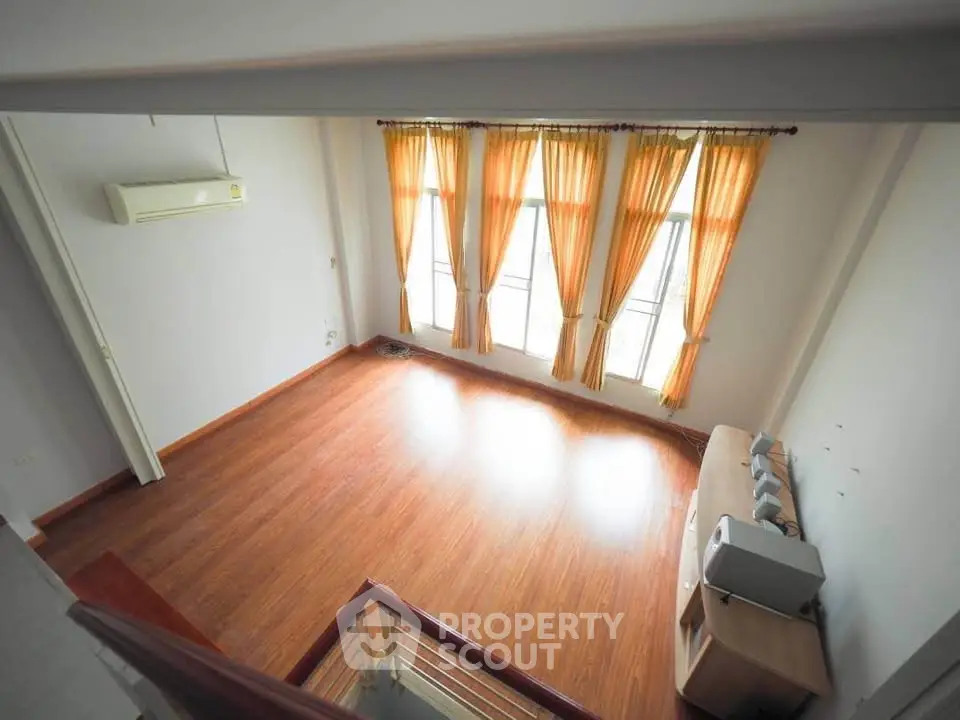 Spacious living room with wooden flooring and large windows with curtains