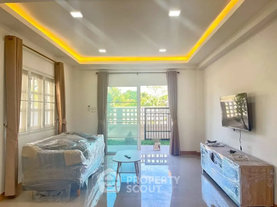 Spacious living room with modern lighting and large windows opening to a garden view.