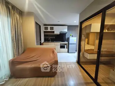 Modern studio apartment with cozy living area and compact kitchen featuring sleek appliances.